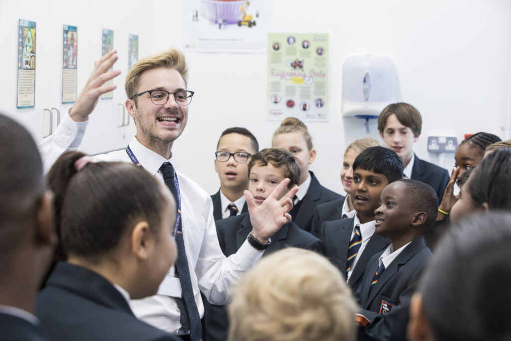 Staff member enthusiastically talking to students in a group around him.