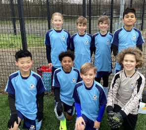 A photo of the Leigh Stationers' Primary Academy Football Team posing for the camera, after having just won a match.