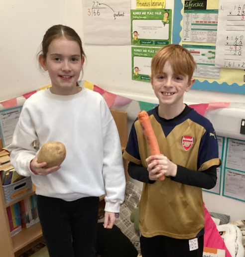 Two pupils, a boy and a girl, are pictured smiling for the camera during Numbers Day at Leigh Stationers' Primary Academy.